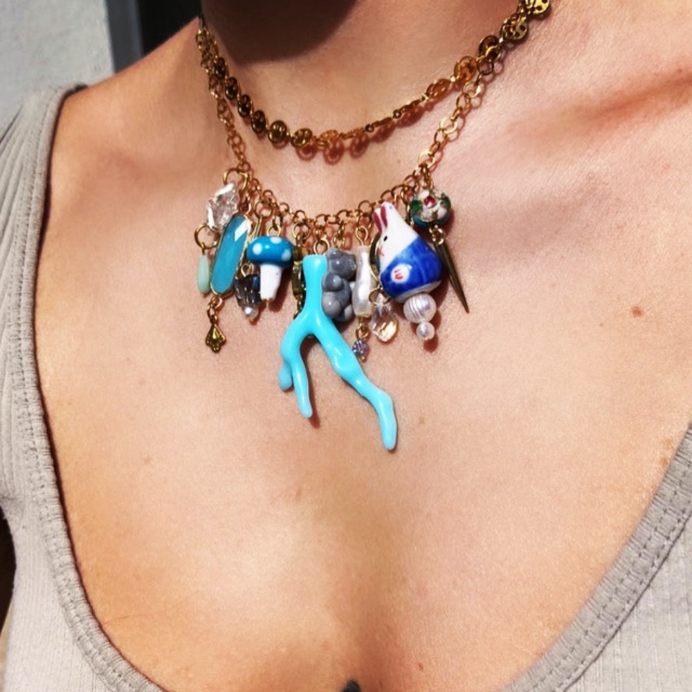 Gold steel necklace with mixed materials statement charms.